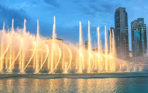 Dubai Fountain Boardwalk with illuminated water jets and city skyline.