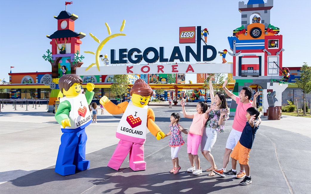 Family posing with Lego figures at Legoland Korea entrance.