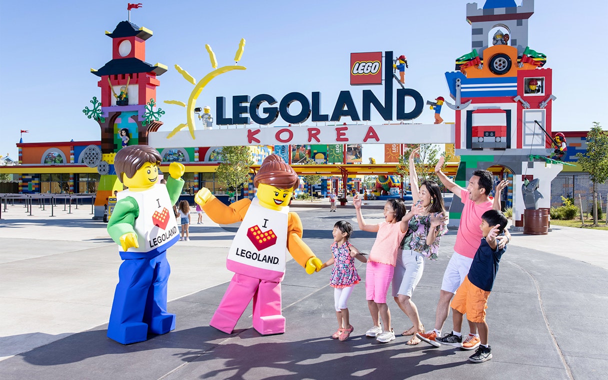 Family posing with Lego figures at Legoland Korea entrance.