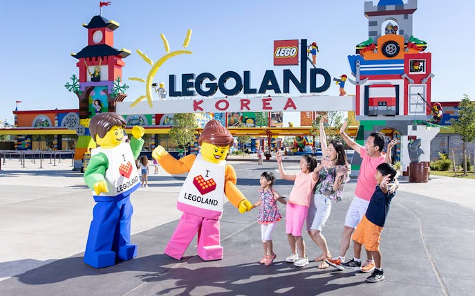 Family posing with Lego figures at Legoland Korea entrance.