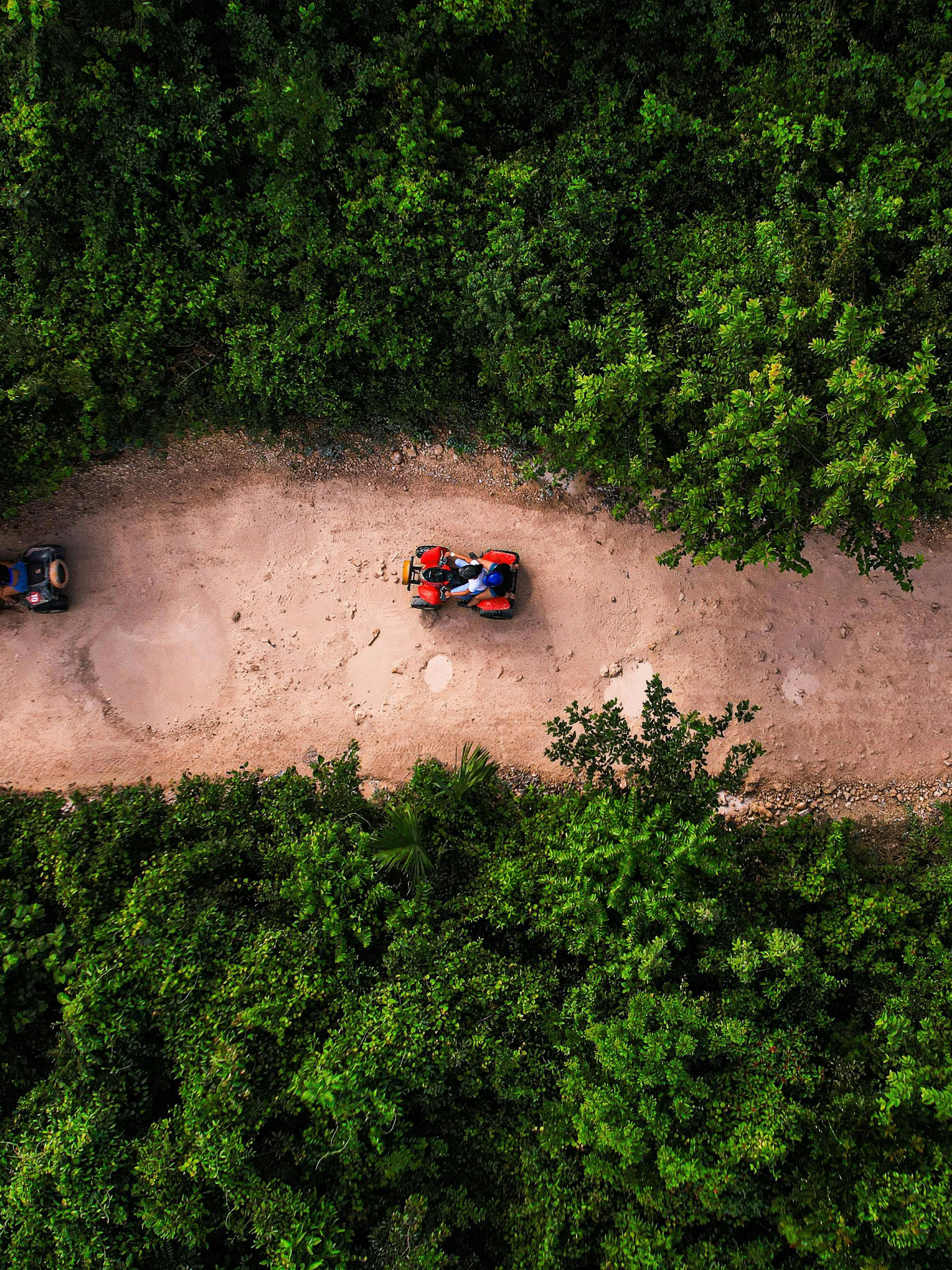 ATVs on a dirt path through lush greenery at Cancun Extreme Adventuring Park.