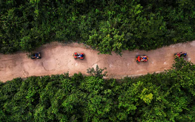 ATVs on a dirt path through lush greenery at Cancun Extreme Adventuring Park.