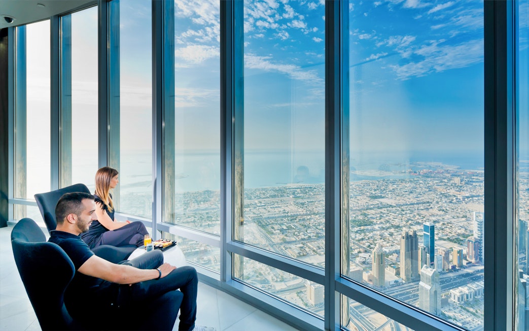 Visitors enjoying panoramic views from Burj Khalifa Level 124, overlooking Dubai cityscape.