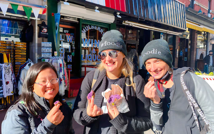 Tourists savoring crepes at Ahoy New York Food Tours in front of a local shop.
