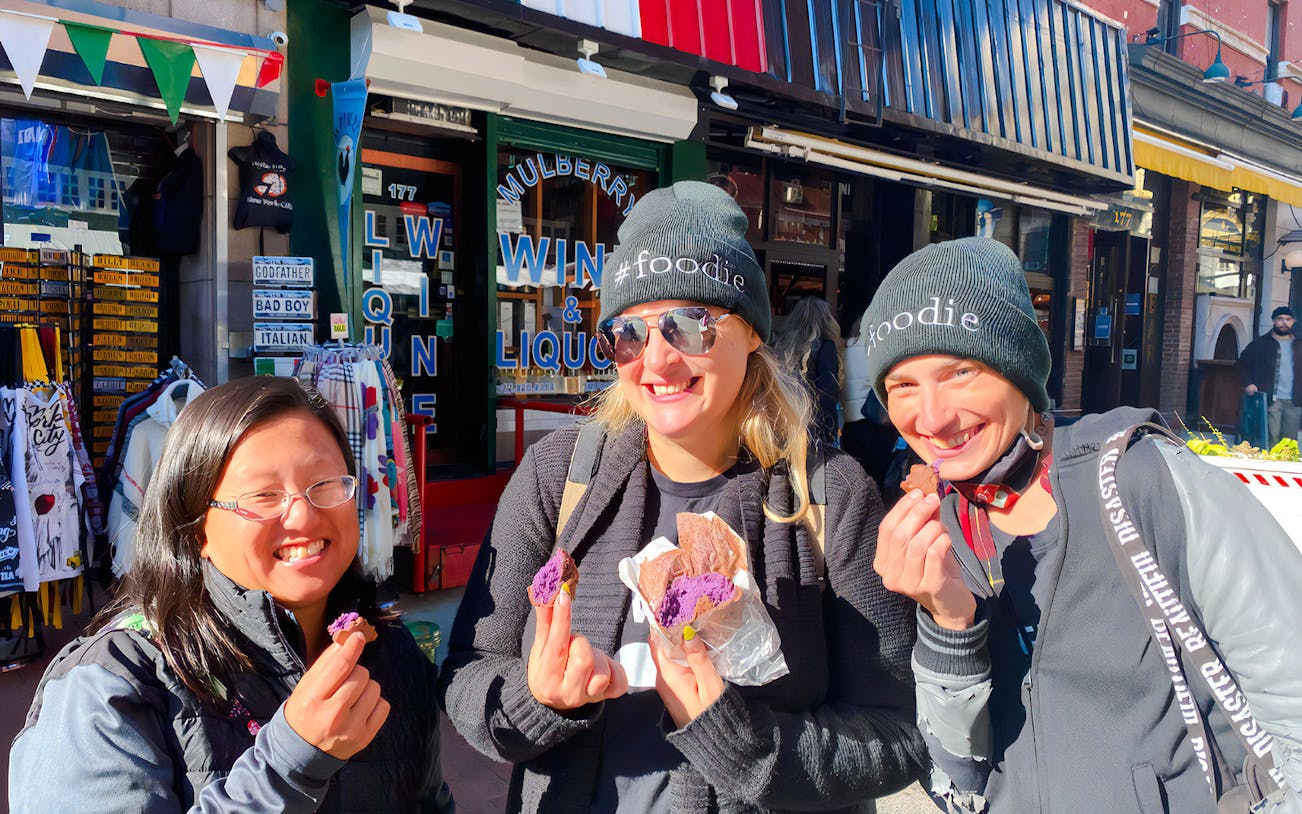Tourists savoring crepes at Ahoy New York Food Tours in front of a local shop.