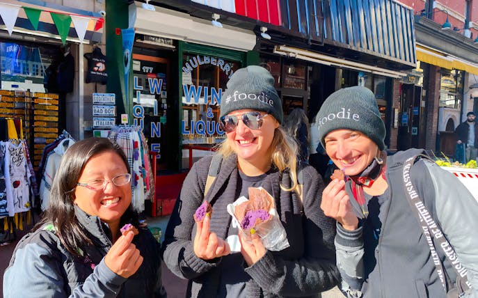 Tourists savoring crepes at Ahoy New York Food Tours in front of a local shop.