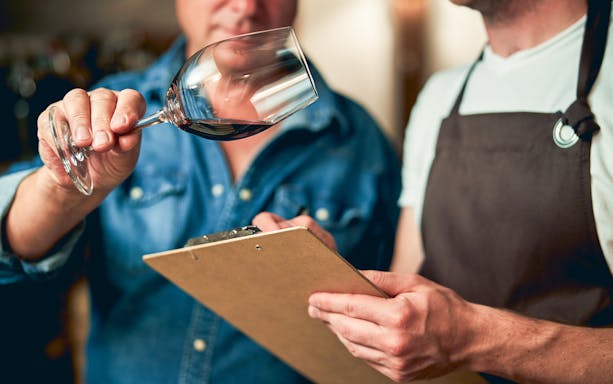 Wine expert evaluating a glass during a blending workshop at a winery.