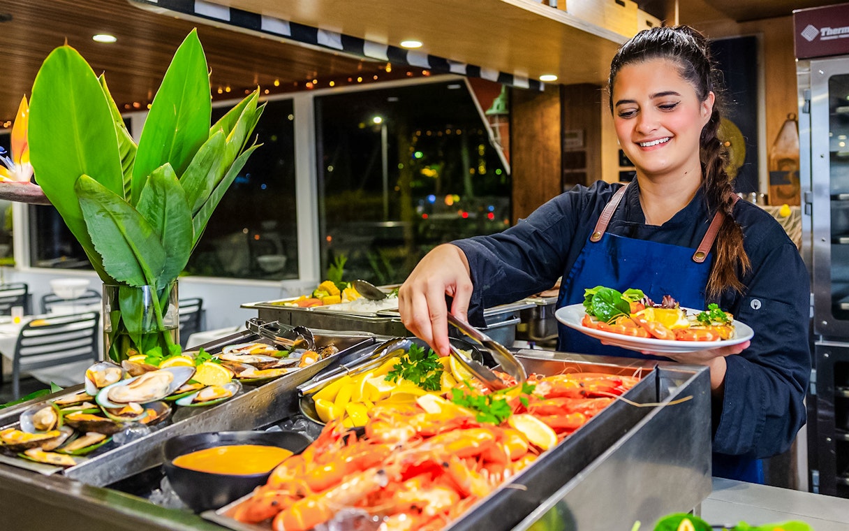Server preparing seafood platter on Gold Coast dinner cruise.
