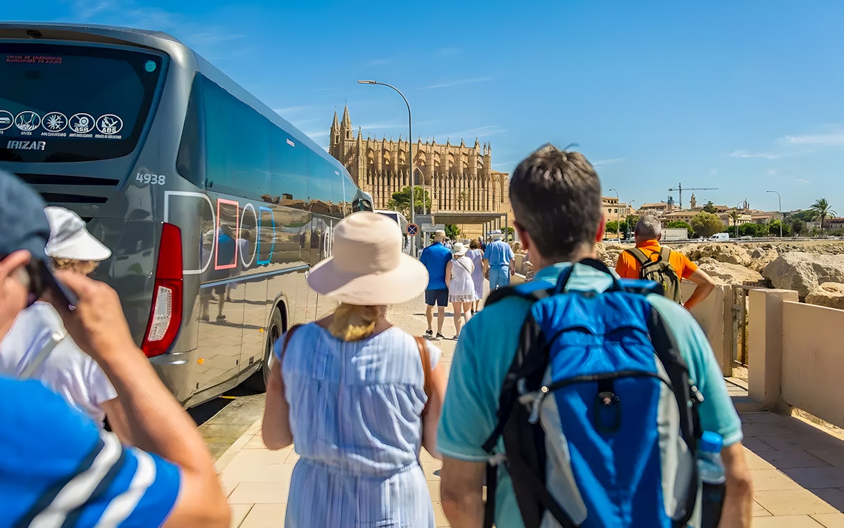Visitors walking from bus towards Palma Cathedral in Mallorca.
