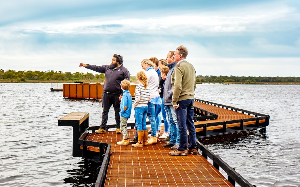 Guide leading a group on a boardwalk during the Tae Rak Guided Cultural Walk.
