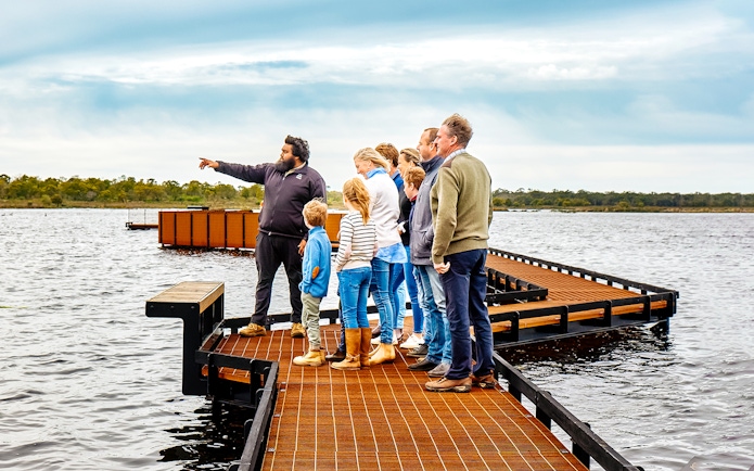 Guide leading a group on a boardwalk during the Tae Rak Guided Cultural Walk.