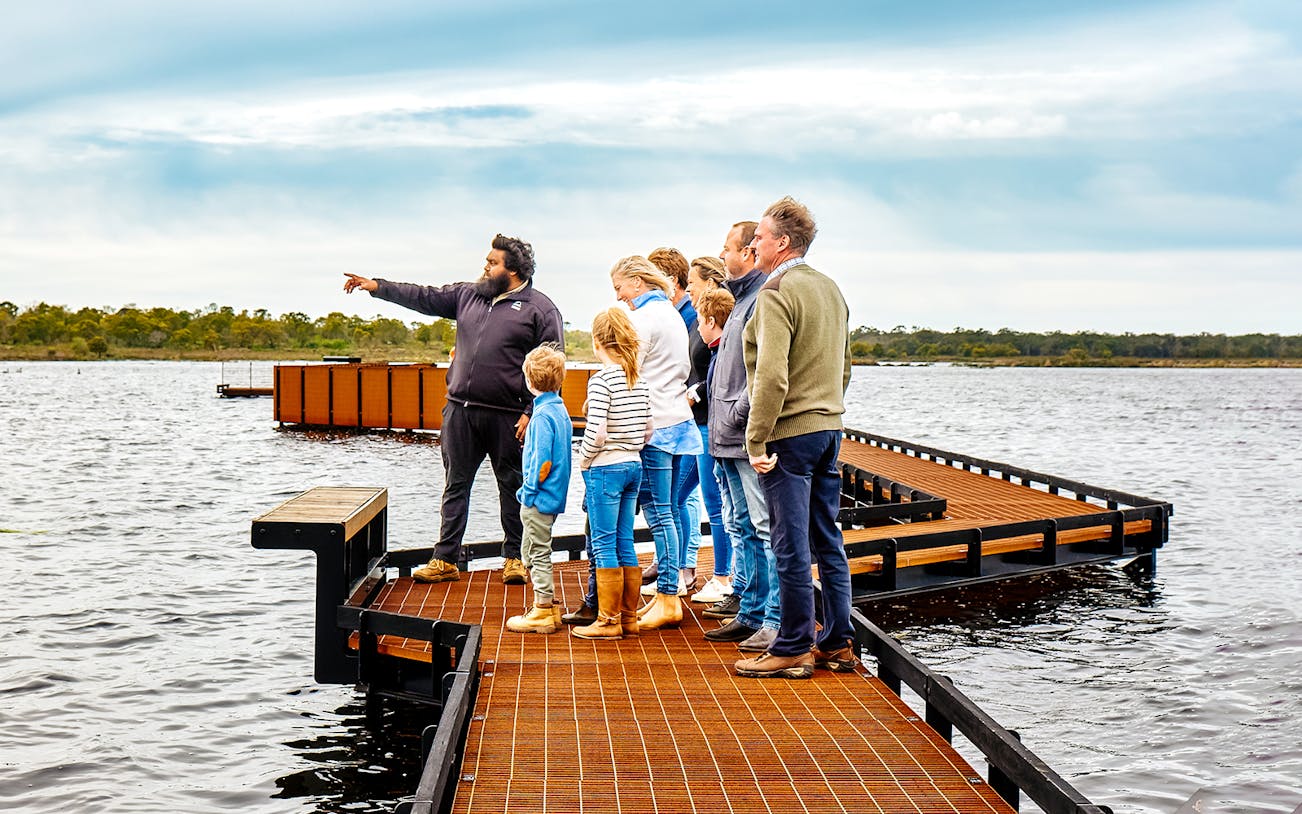 Guide leading a group on a boardwalk during the Tae Rak Guided Cultural Walk.