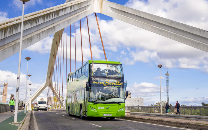Seville hop-on hop-off bus crossing a bridge with modern architecture.