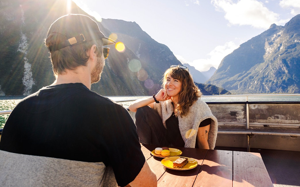 Couple enjoying snacks on viewing deck, Haven, Milford Sound.