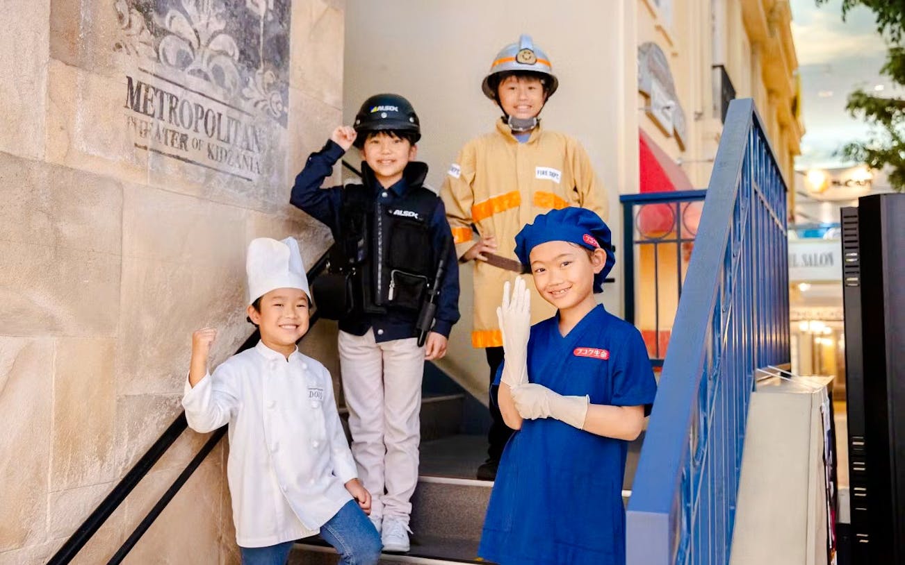 Children in various uniforms at KidZania Osaka Koshien, engaging in role-play activities.