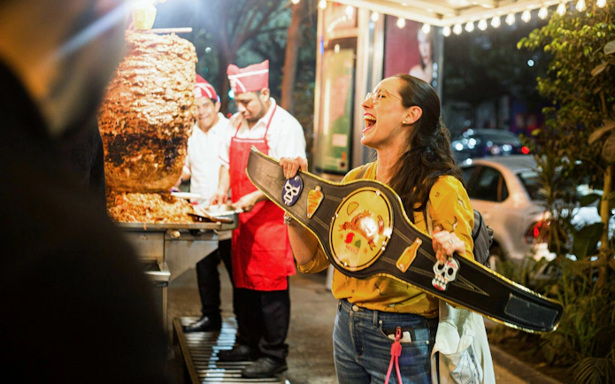 Street vendor serving tacos al pastor at night in Mexico City.
