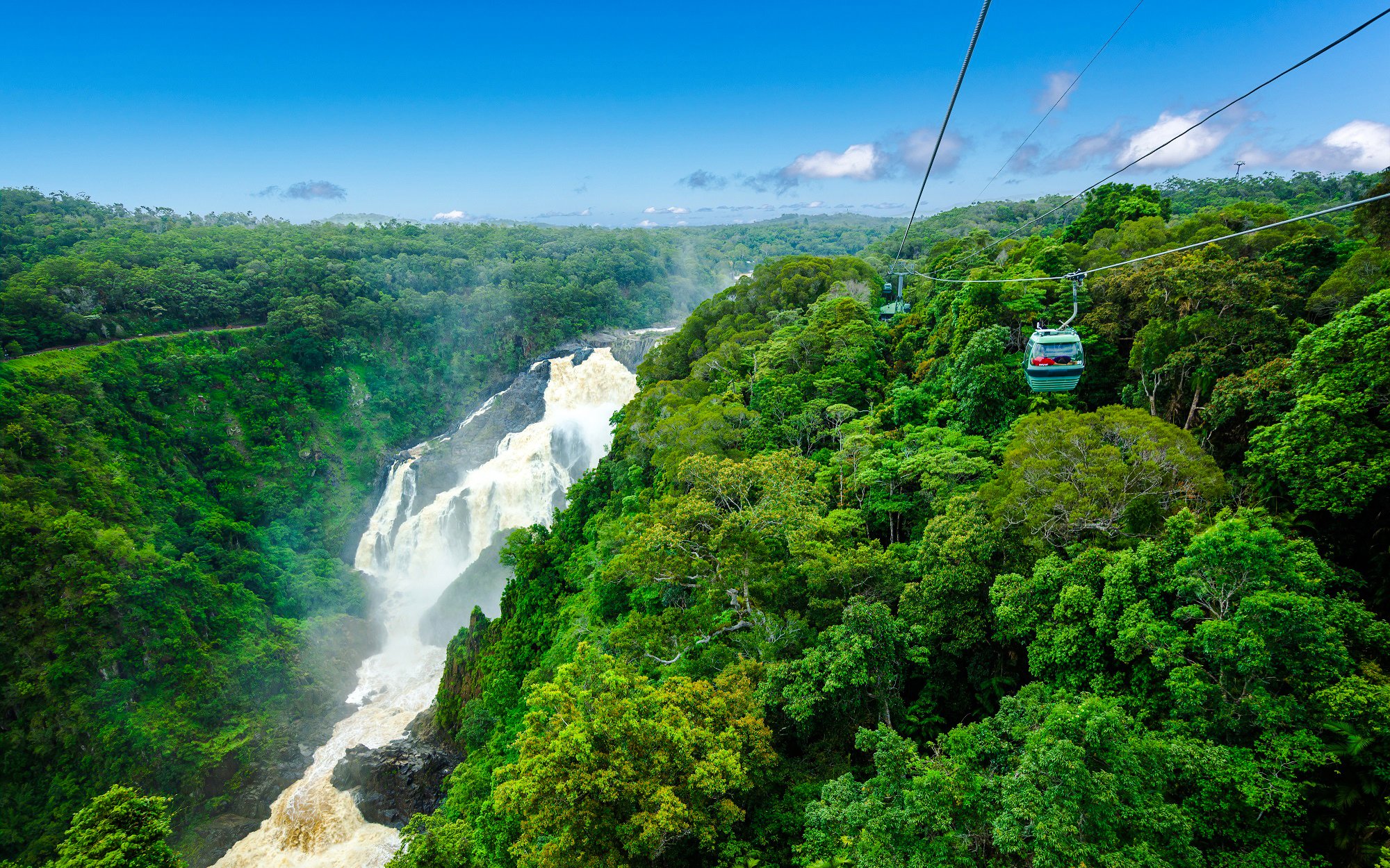 Skyrail gondola over rainforest with waterfall view on Kuranda tour, Australia.