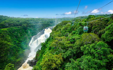 Skyrail gondola over rainforest with waterfall view on Kuranda tour, Australia.