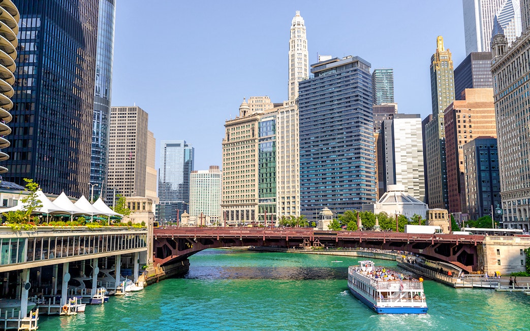 Cruise boat on Chicago River with city skyscrapers in the background.