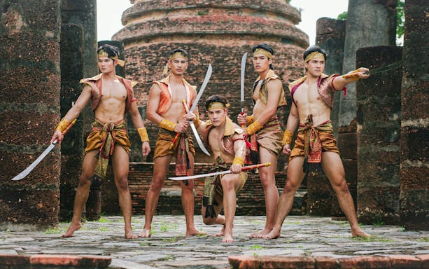 Performers in traditional attire with swords at Siam Fantasy belief and faith show.
