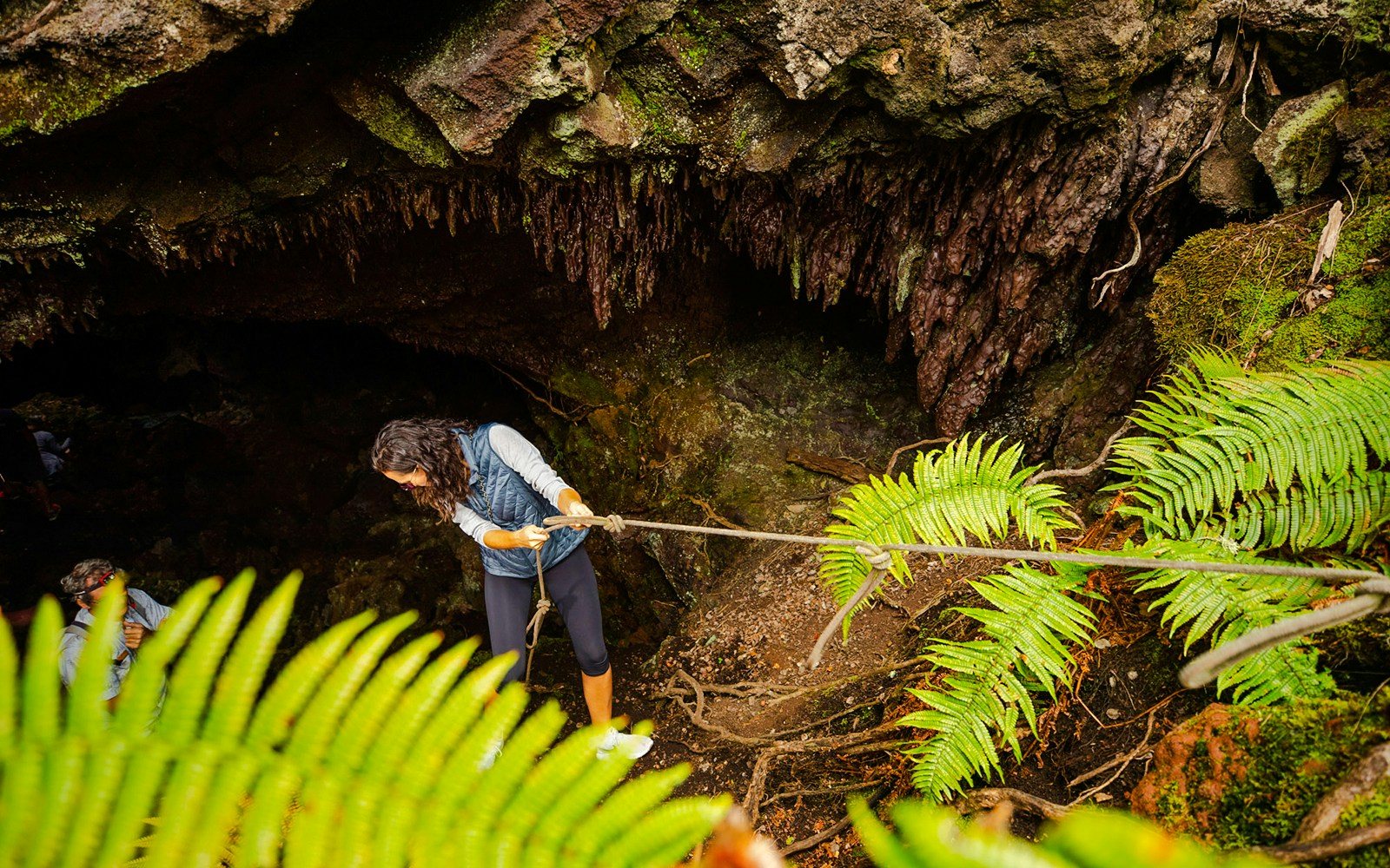 Guests descending into a cave on the Hualalai Volcano during the Hidden Craters Hike.