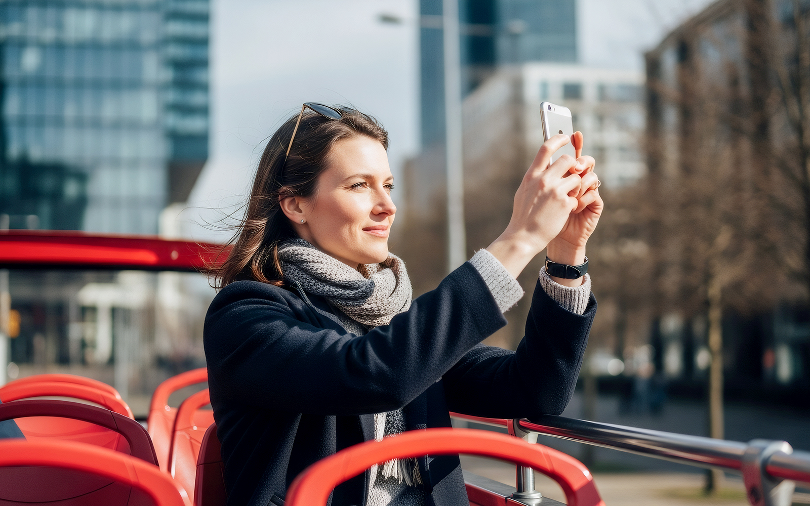Tourist taking photo on open-top hop on hop off bus in city.