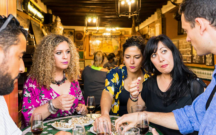 Group enjoying tapas and drinks at a traditional bar in Seville during a tasting tour.