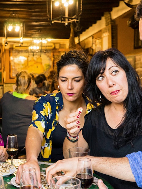 Group enjoying tapas and drinks at a traditional bar in Seville during a tasting tour.