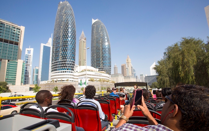 Open-top bus tour passing DAMAC Park Towers in Dubai.