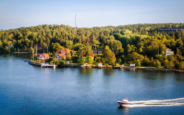Stockholm archipelago with red cottages and boat on the water.