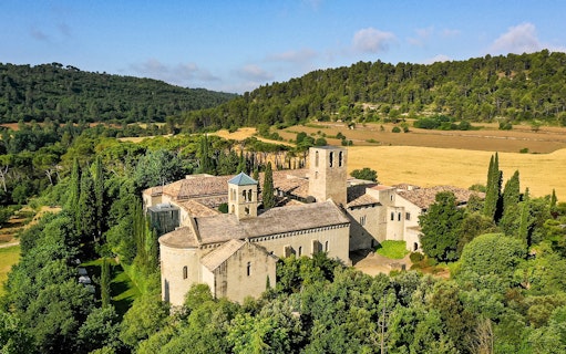 Medieval monastery at Món Sant Benet surrounded by lush greenery and rolling hills.