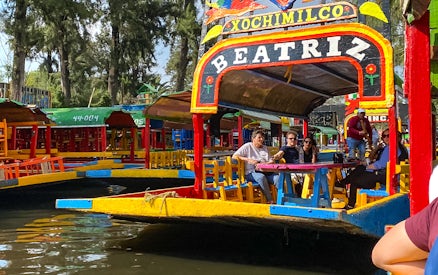 Colorful trajinera boat with tourists on a Xochimilco canal tour in Mexico City.