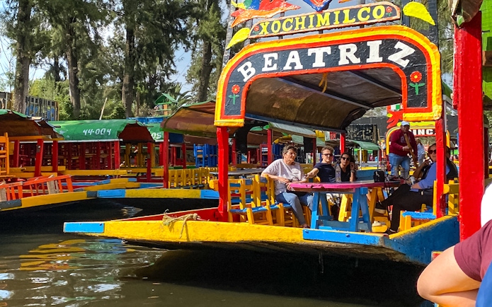 Colorful trajinera boat with tourists on a Xochimilco canal tour in Mexico City.