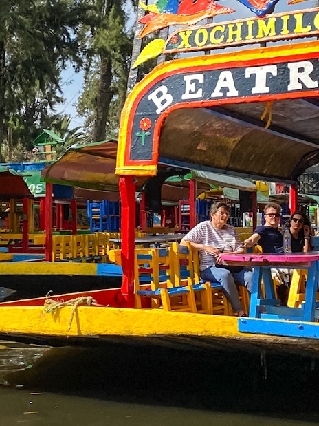 Colorful trajinera boat with tourists on a Xochimilco canal tour in Mexico City.