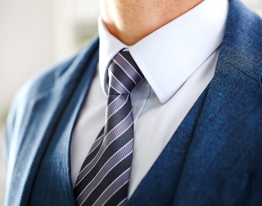 Formal attire with a blue suit and striped tie for Moulin Rouge dress code.