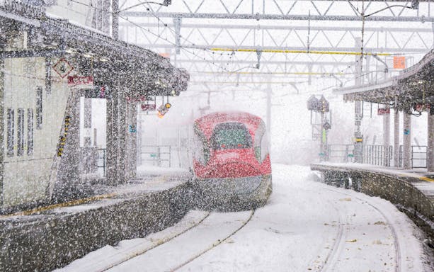Japanese bullet train arriving at snowy station.