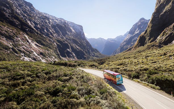 Bus traveling through mountainous landscape en route to Milford Sound from Te Anau.