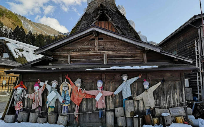 Scarecrow display in front of a traditional gassho-zukuri house in Shirakawa-go village.