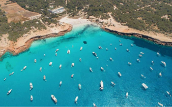 Boats anchored in turquoise waters near Formentera coast, viewed from above.