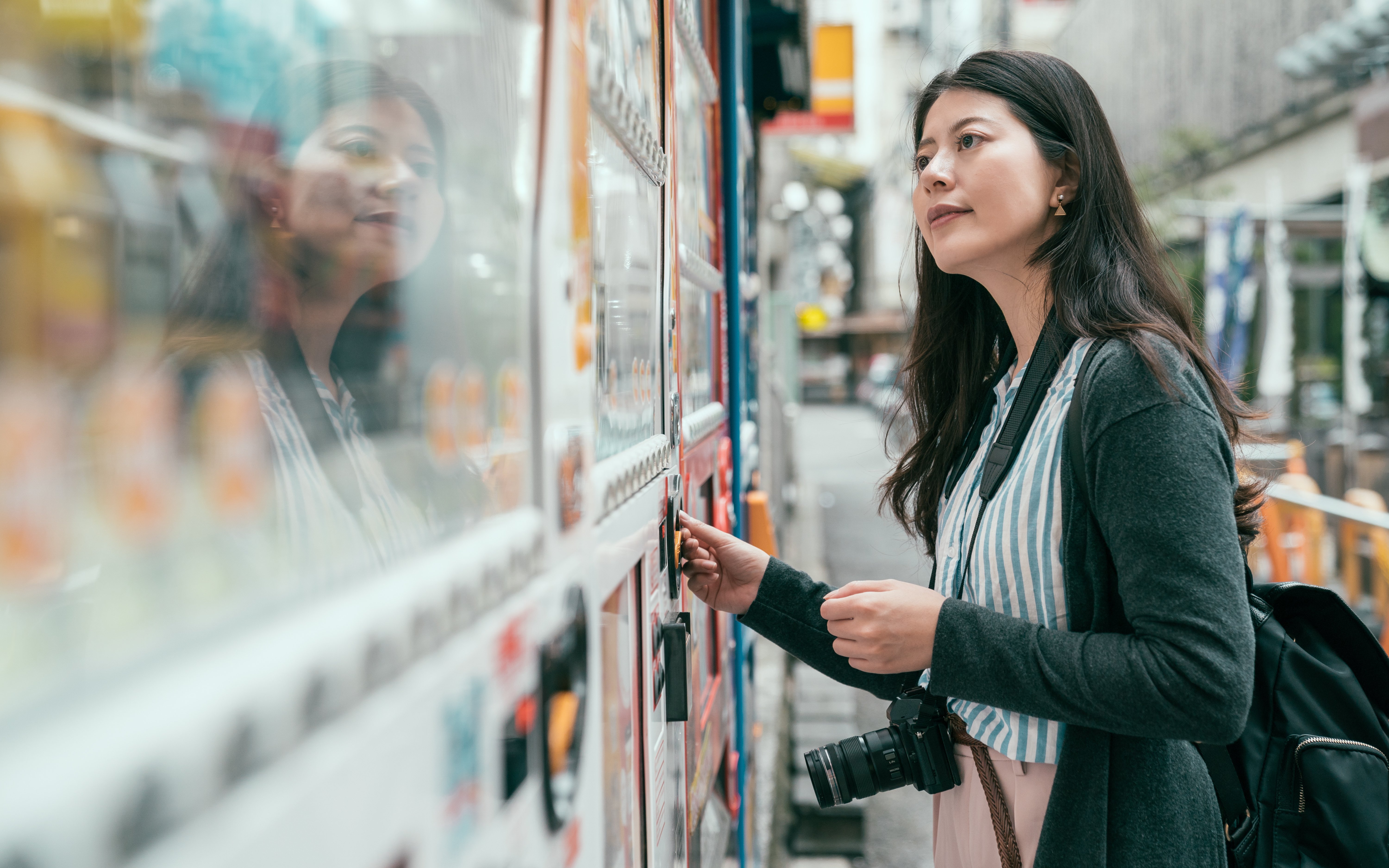 Person using a Japanese vending machine on a city street.
