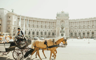Horse-drawn carriage in front of Hofburg Palace, Vienna, part of self-guided city exploration game.