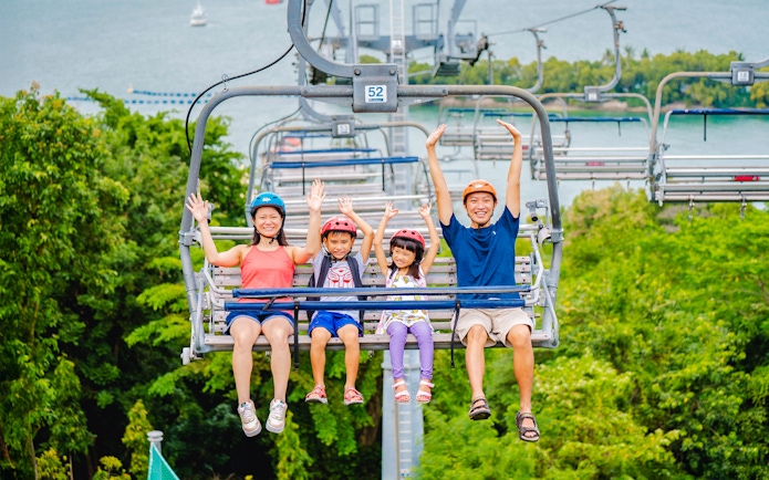 Family enjoying the Skyride in Singapore with lush greenery and ocean view.
