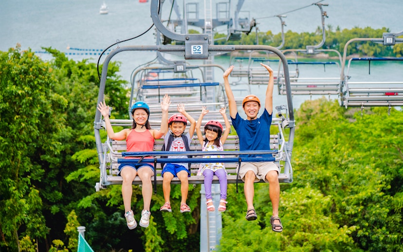 Family enjoying the Skyride in Singapore with lush greenery and ocean view.
