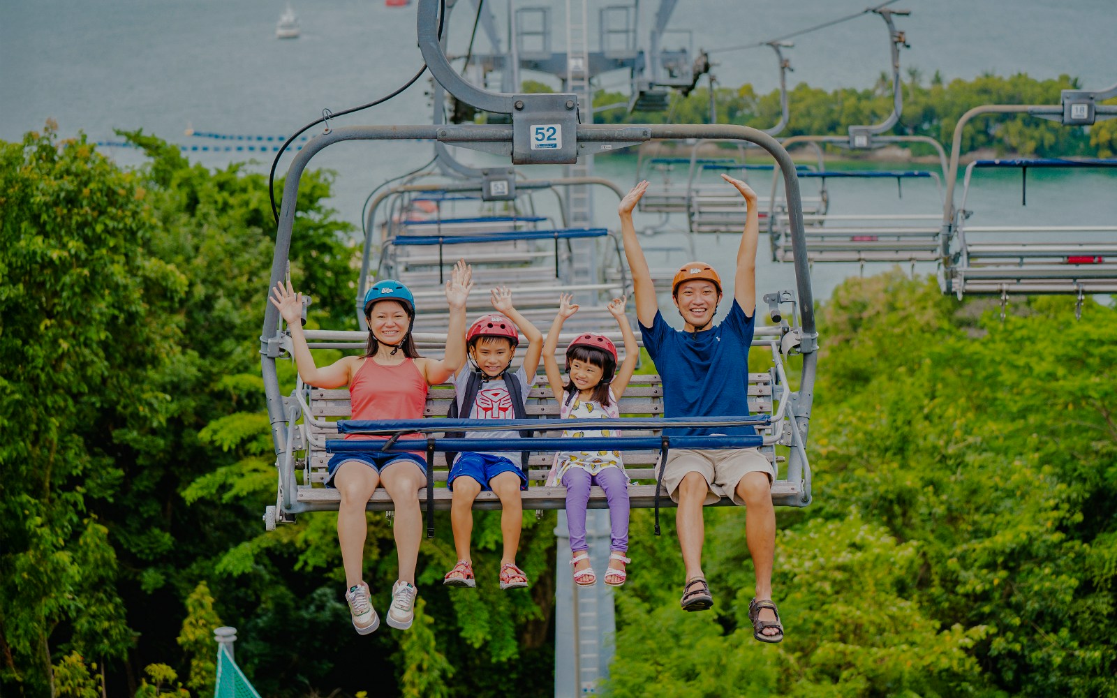 Family enjoying the Skyride in Singapore with lush greenery and ocean view.