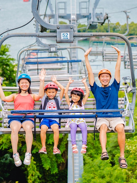 Family enjoying the Skyride in Singapore with lush greenery and ocean view.