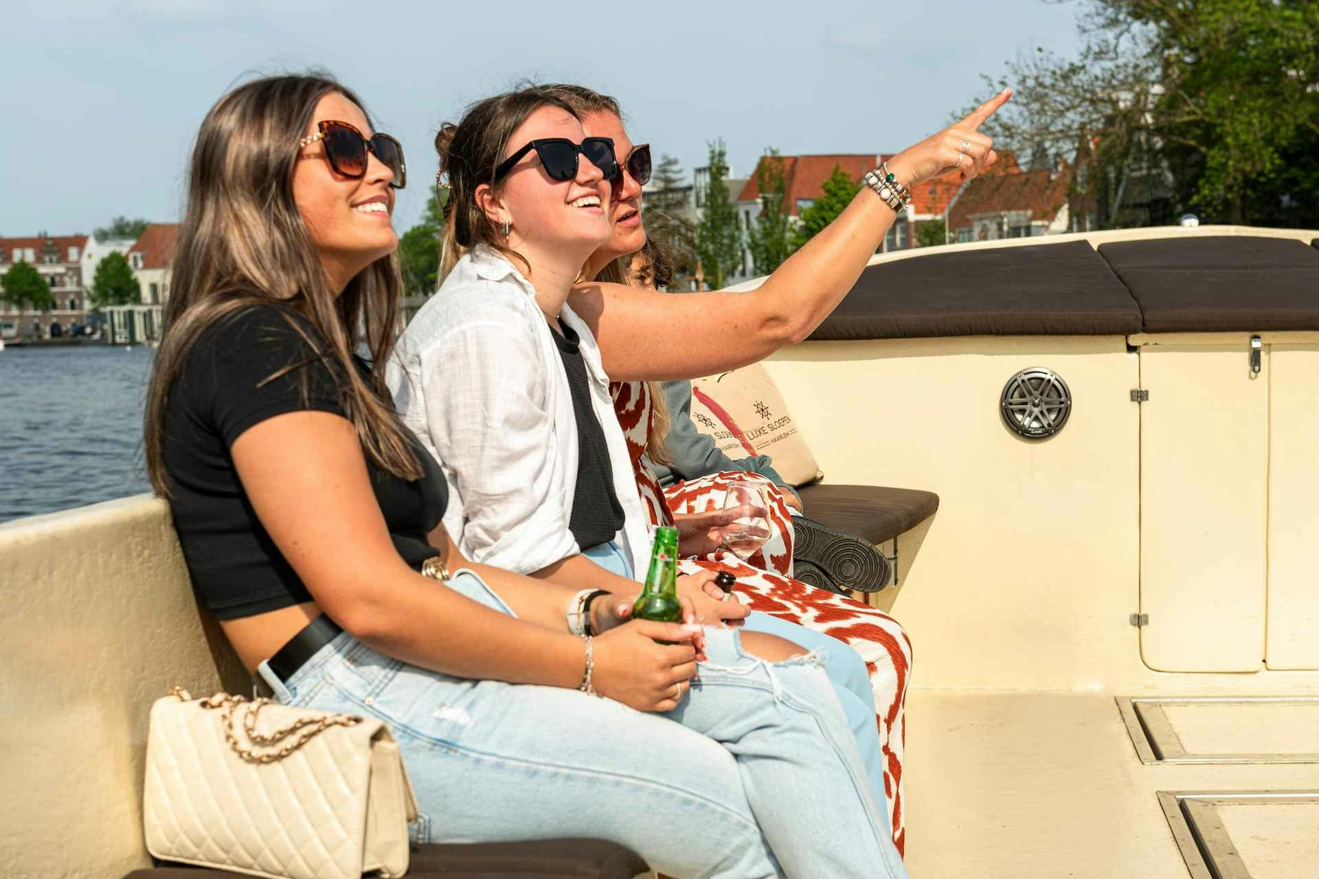 Tourists enjoying a Harlem canal cruise on an open boat, one pointing at a landmark.