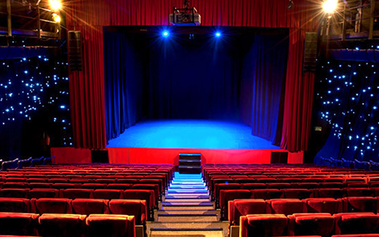 Seville Flamenco Theatre stage with red curtains and seating.