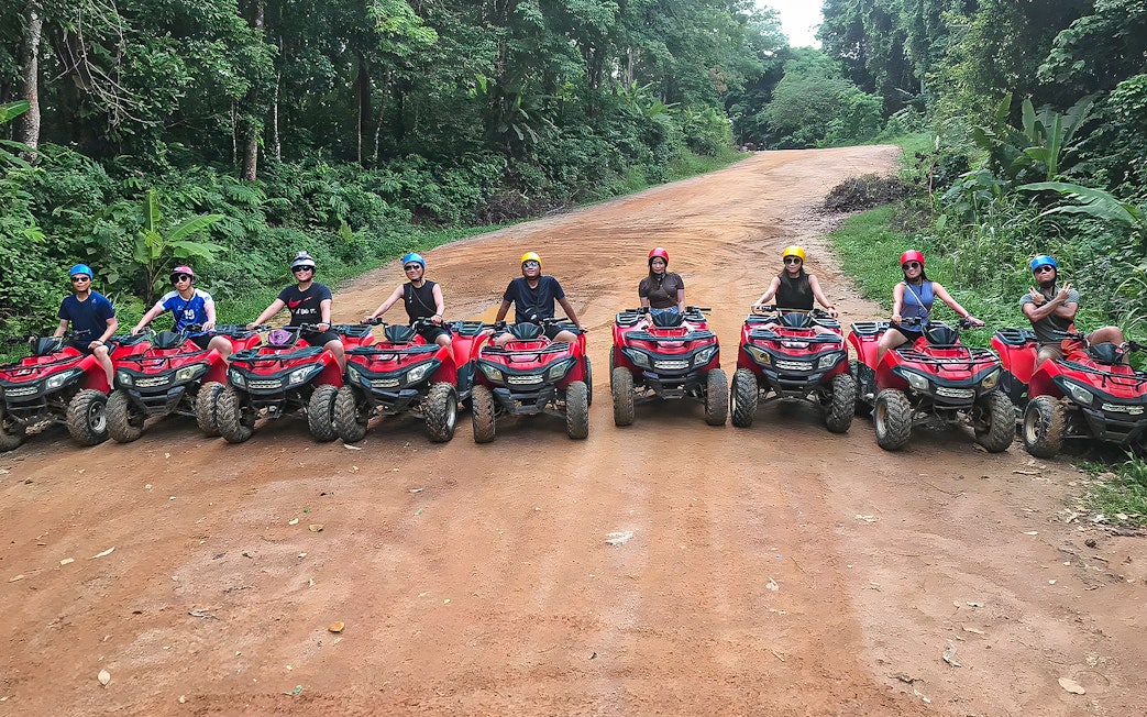Tourists on ATVs in Phuket, riding through lush forest trails.