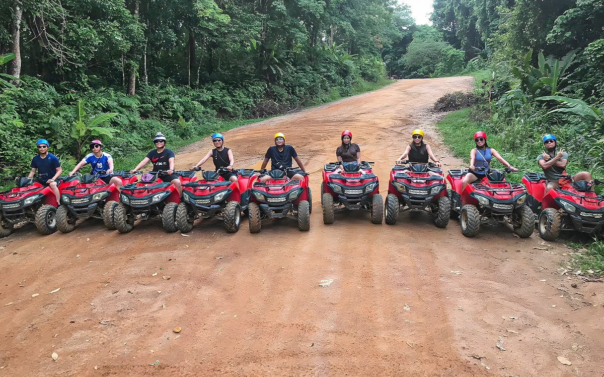 Tourists on ATVs in Phuket, riding through lush forest trails.
