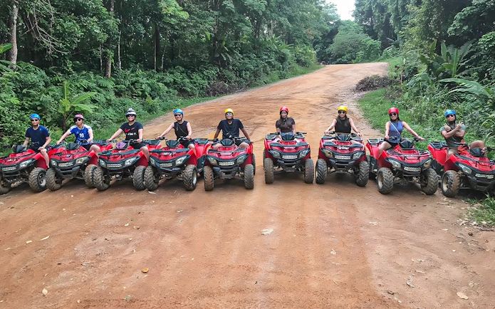 Tourists on ATVs in Phuket, riding through lush forest trails.